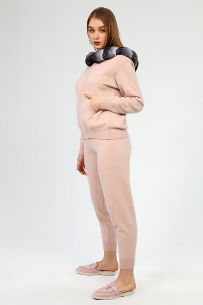 Woman wearing a pink outfit with a chinchilla fur hoodie on a white background