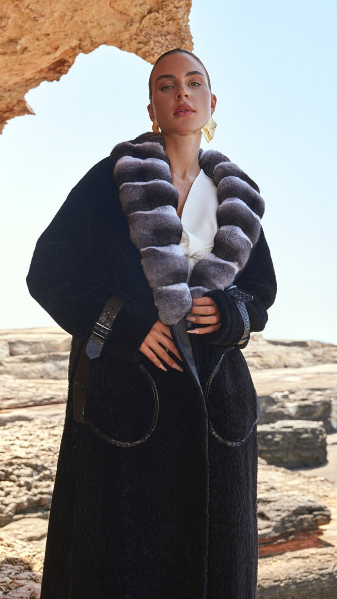Woman wearing a long black coat with a textured collar in a rocky outdoor setting