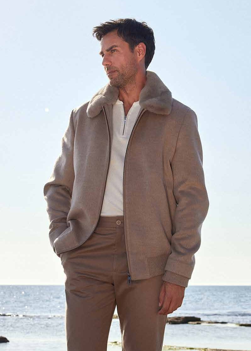 Man in beige outfit standing on rocks by the sea
