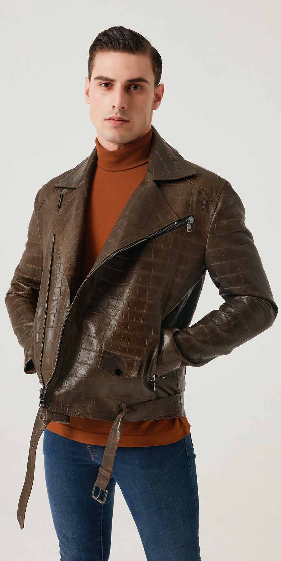 Man wearing a brown leather jacket over an orange sweater on a white background