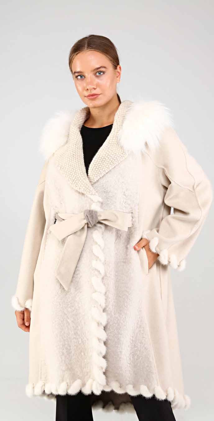 Woman wearing a cream-colored coat with mink and fox fur trim on a plain background