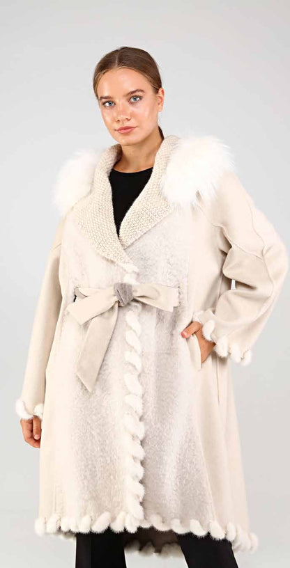 Woman wearing a cream-colored coat with mink and fox fur trim on a plain background