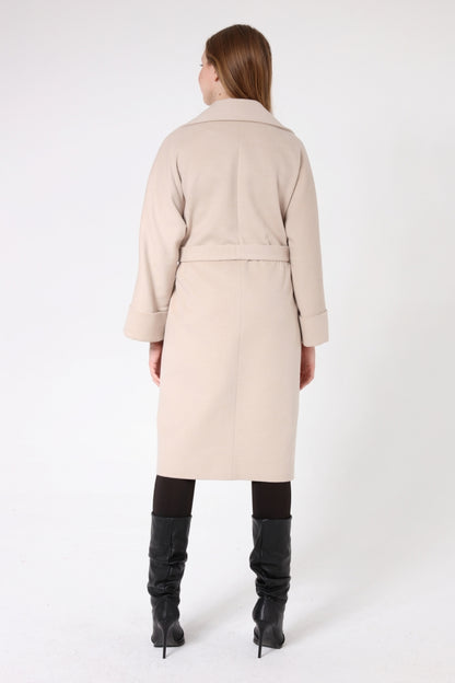 Woman wearing a beige coat and black boots on a white background