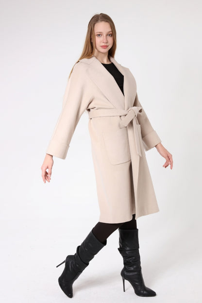 Woman wearing a beige coat with a belt on a white background