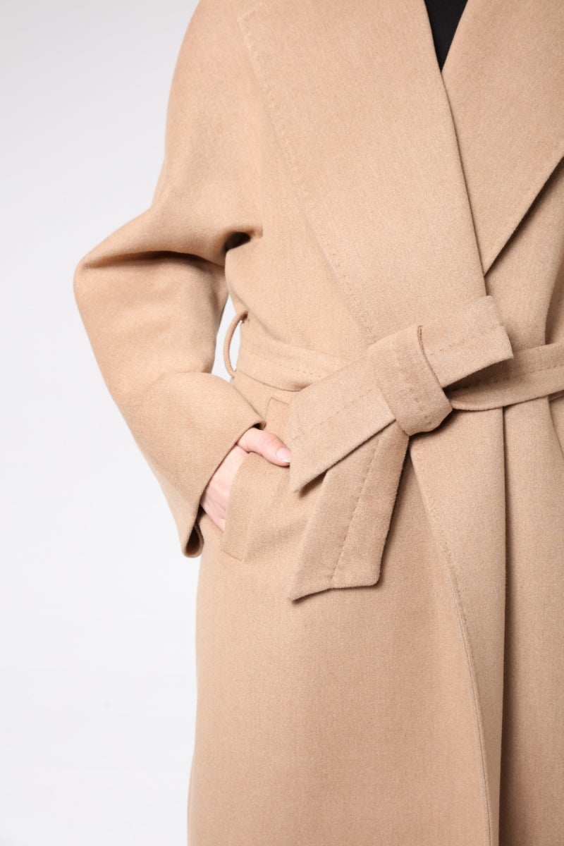Close-up of a beige trench coat with a belt on a light gray background
