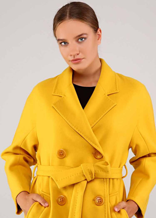 Woman wearing a yellow coat with a plain background