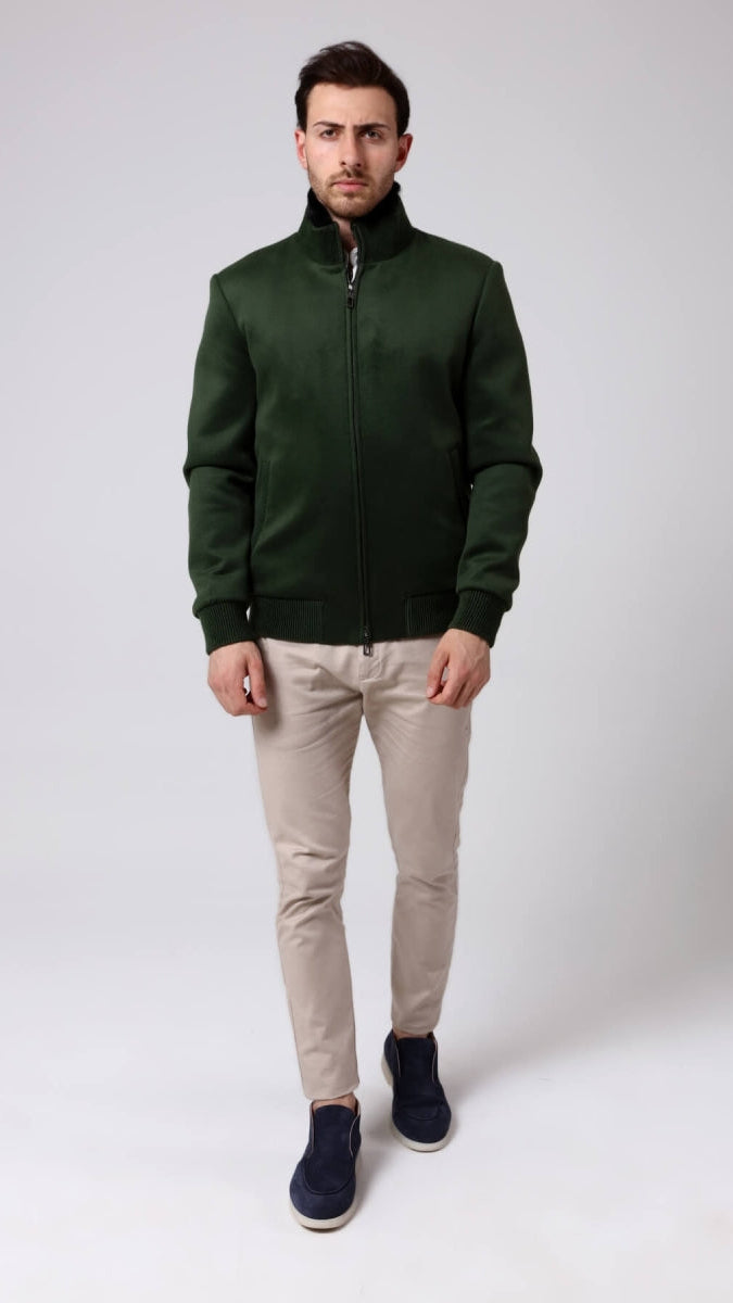 Man wearing a green jacket, beige pants, and black shoes on a white background