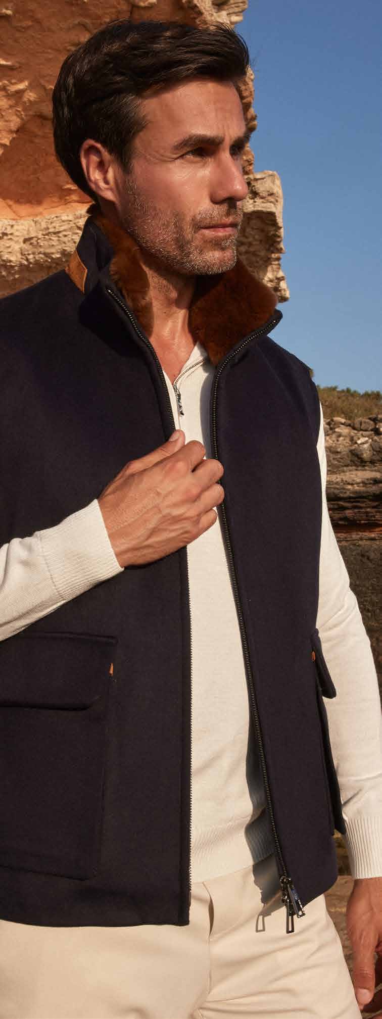 Man wearing a navy vest with fur trim in a natural setting