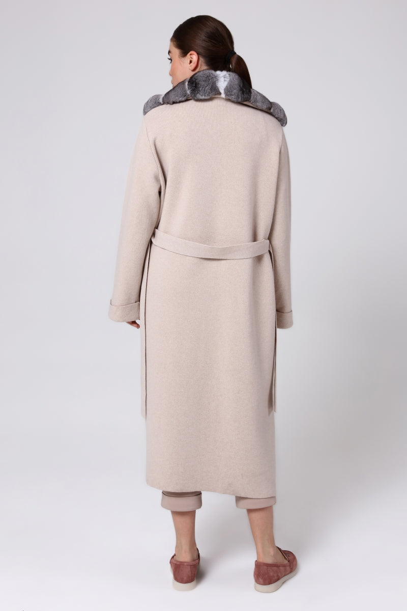 Woman wearing a long beige overcoat with a chinchilla fur on a white background