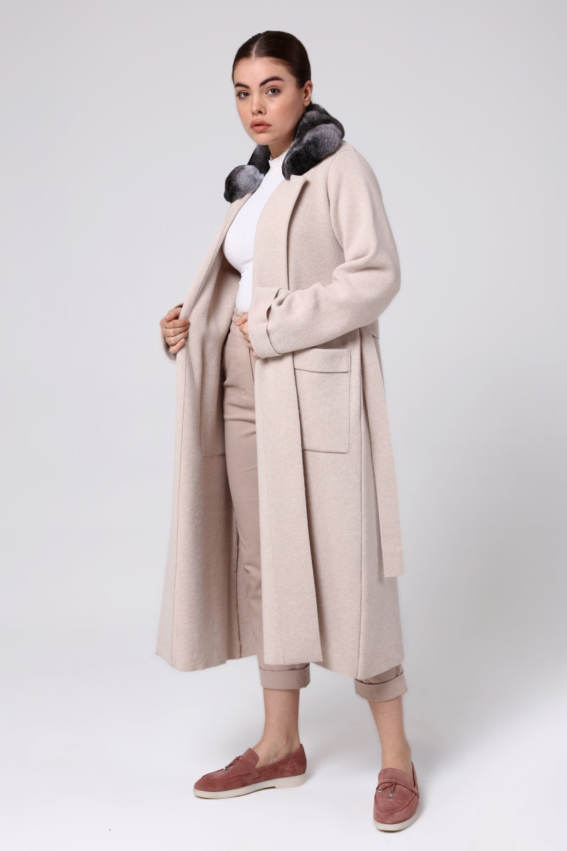 Woman wearing a long beige coat with fur collar on a white background