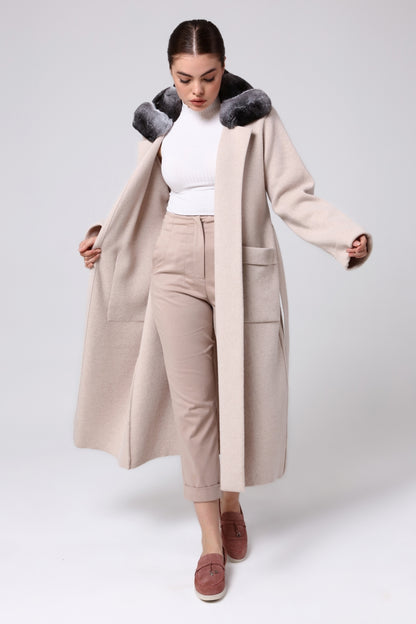 Woman wearing a beige overcoat with a chinchilla fur-lined hood on a white background
