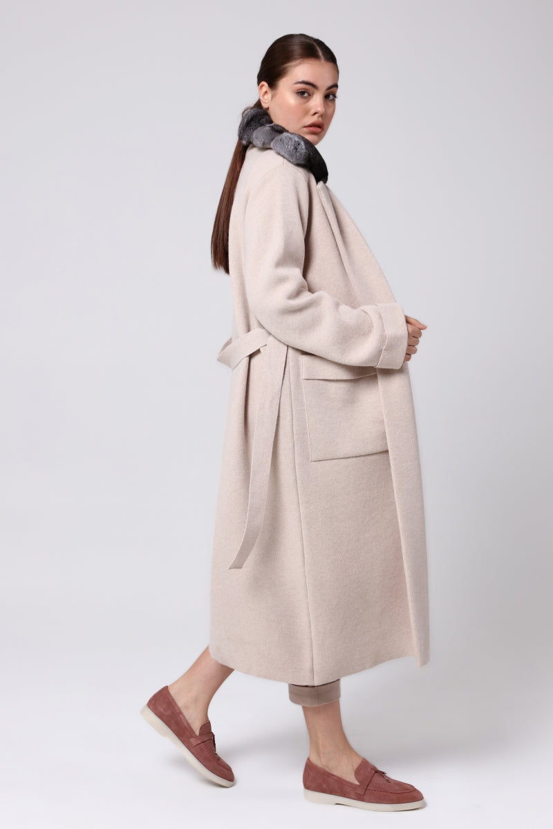 Woman wearing a beige coat with a gray chinchilla on a white background