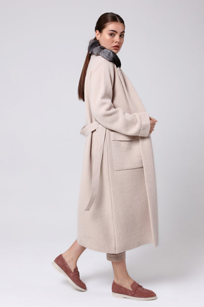 Woman wearing a beige coat with a gray chinchilla on a white background