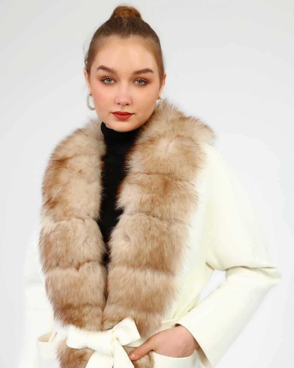 Woman wearing a fox fur with a white cashmere coat on a plain background