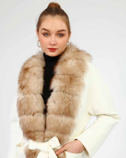 Woman wearing a fox fur with a white cashmere coat on a plain background