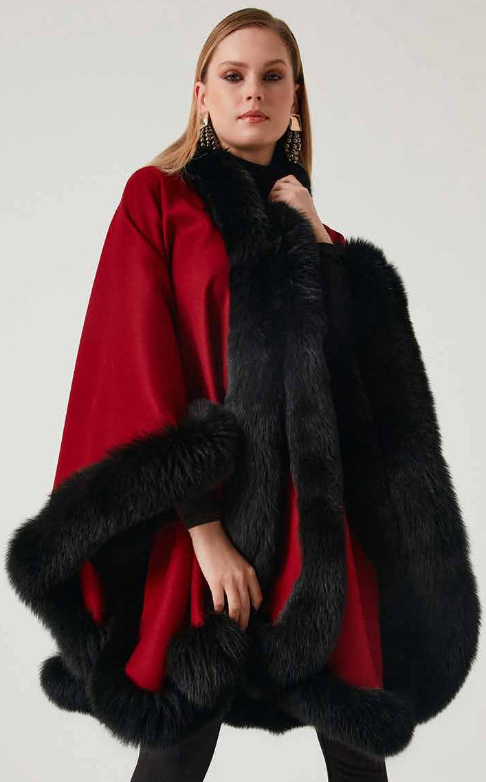 Woman wearing a red alpaca poncho with black fox fur against a white background