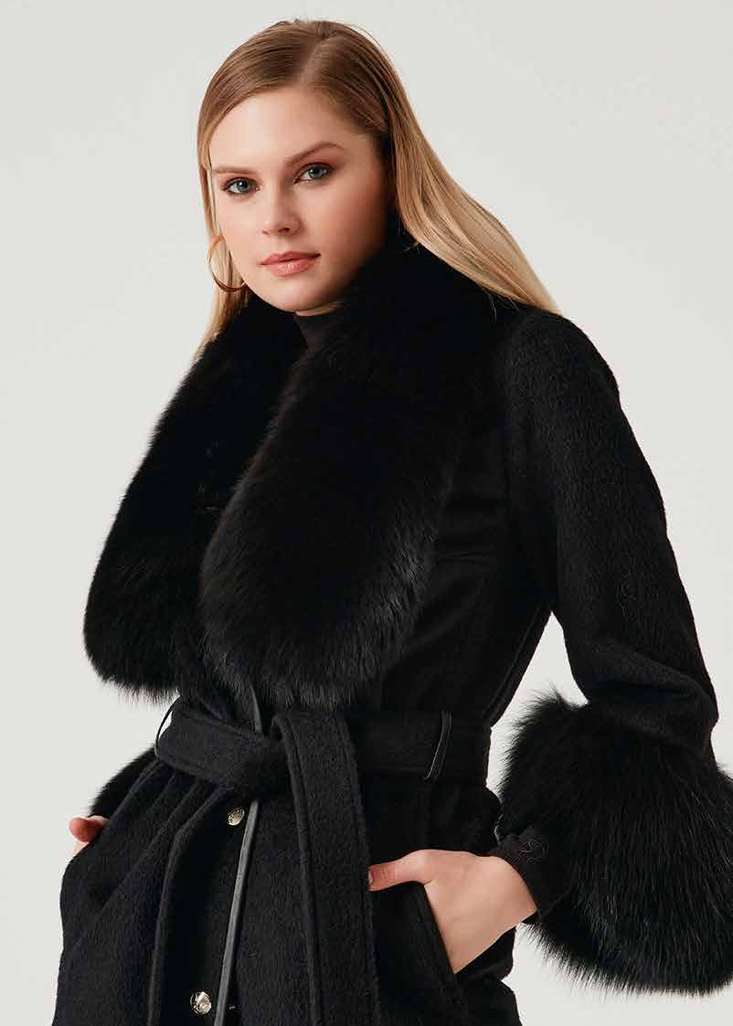 Woman wearing a black coat with fur trim on a white background