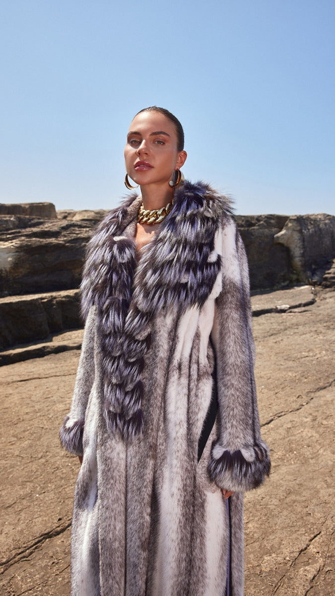 Woman wearing a long fur coat with a rocky landscape background