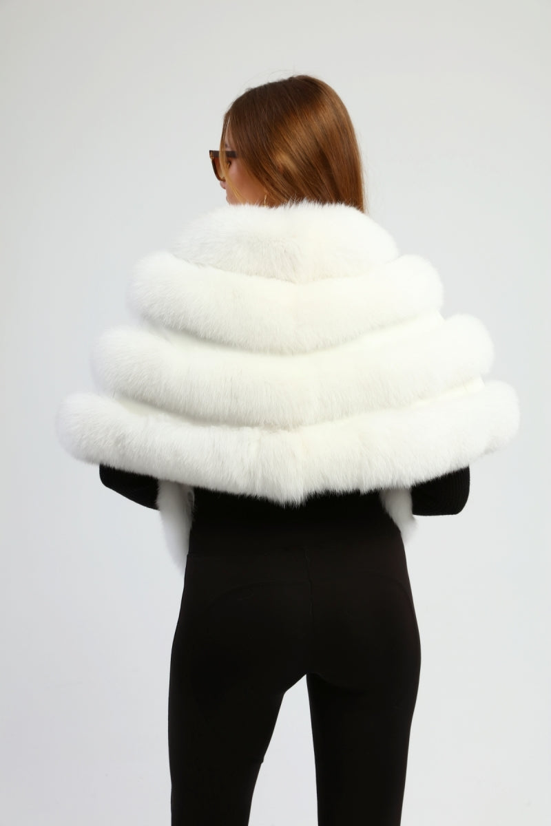 Woman wearing a white fox fur shawl on a plain background