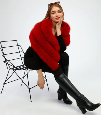Woman wearing a red fox fur shawl sitting on a chair against a white background