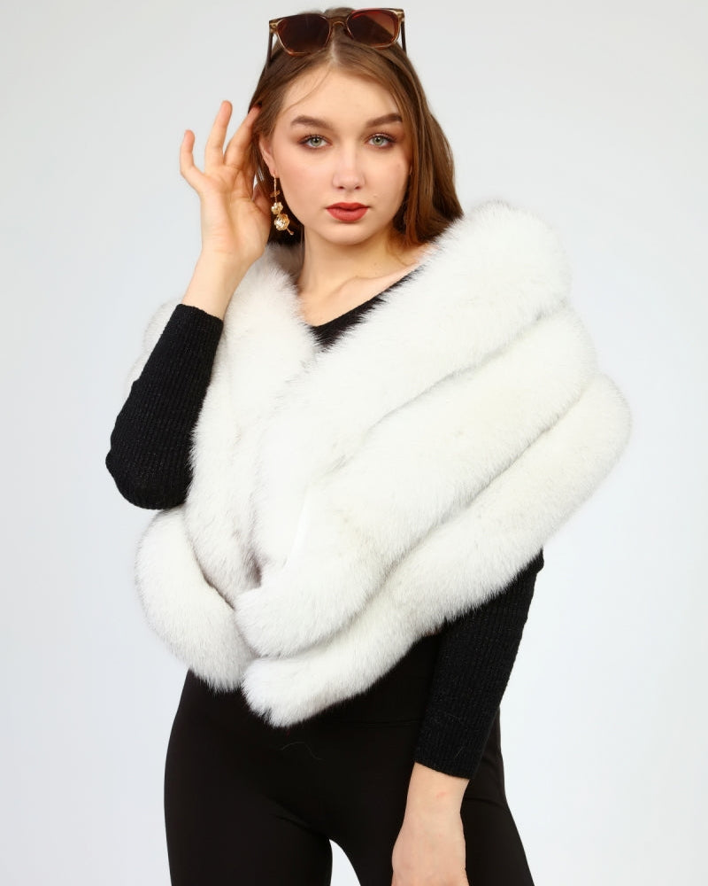 Woman wearing a white fox fur shawl over a black outfit on a light gray background