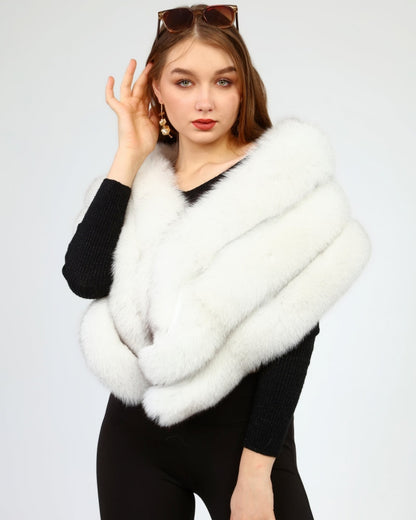 Woman wearing a white fox fur shawl over a black outfit on a light gray background