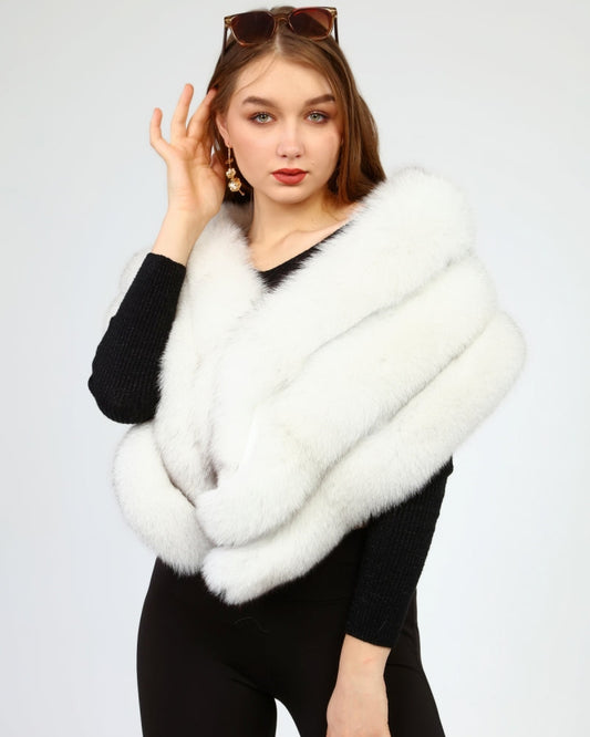 Woman wearing a white fox fur shawl over a black outfit on a light gray background