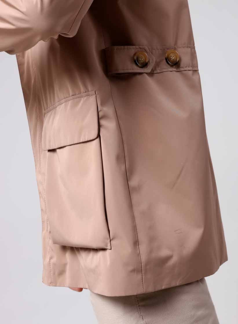 Close-up of a beige jacket with a pocket and button on a light gray background