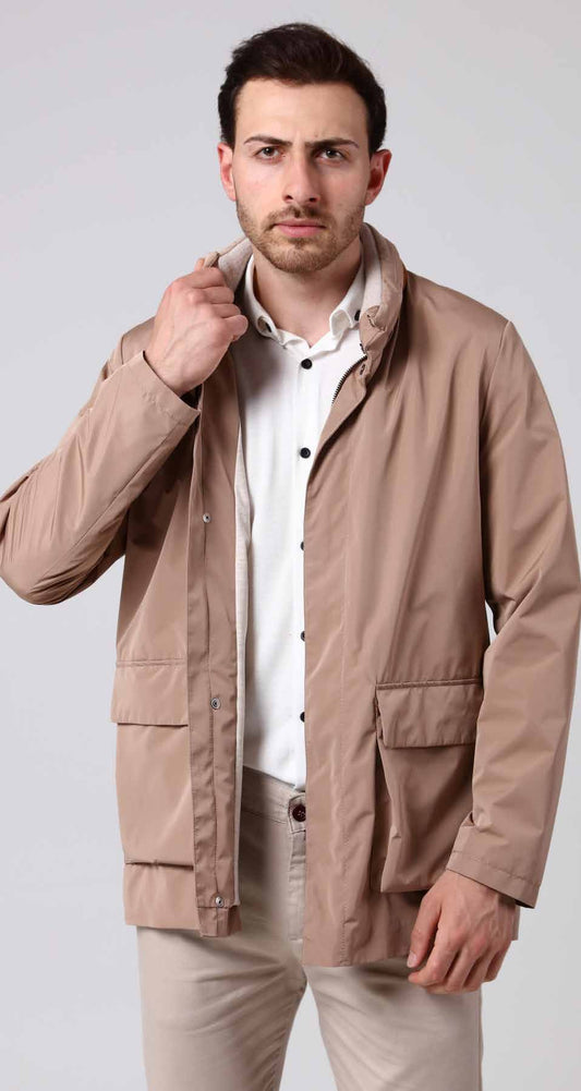 Man wearing a beige jacket over a white shirt on a light gray background