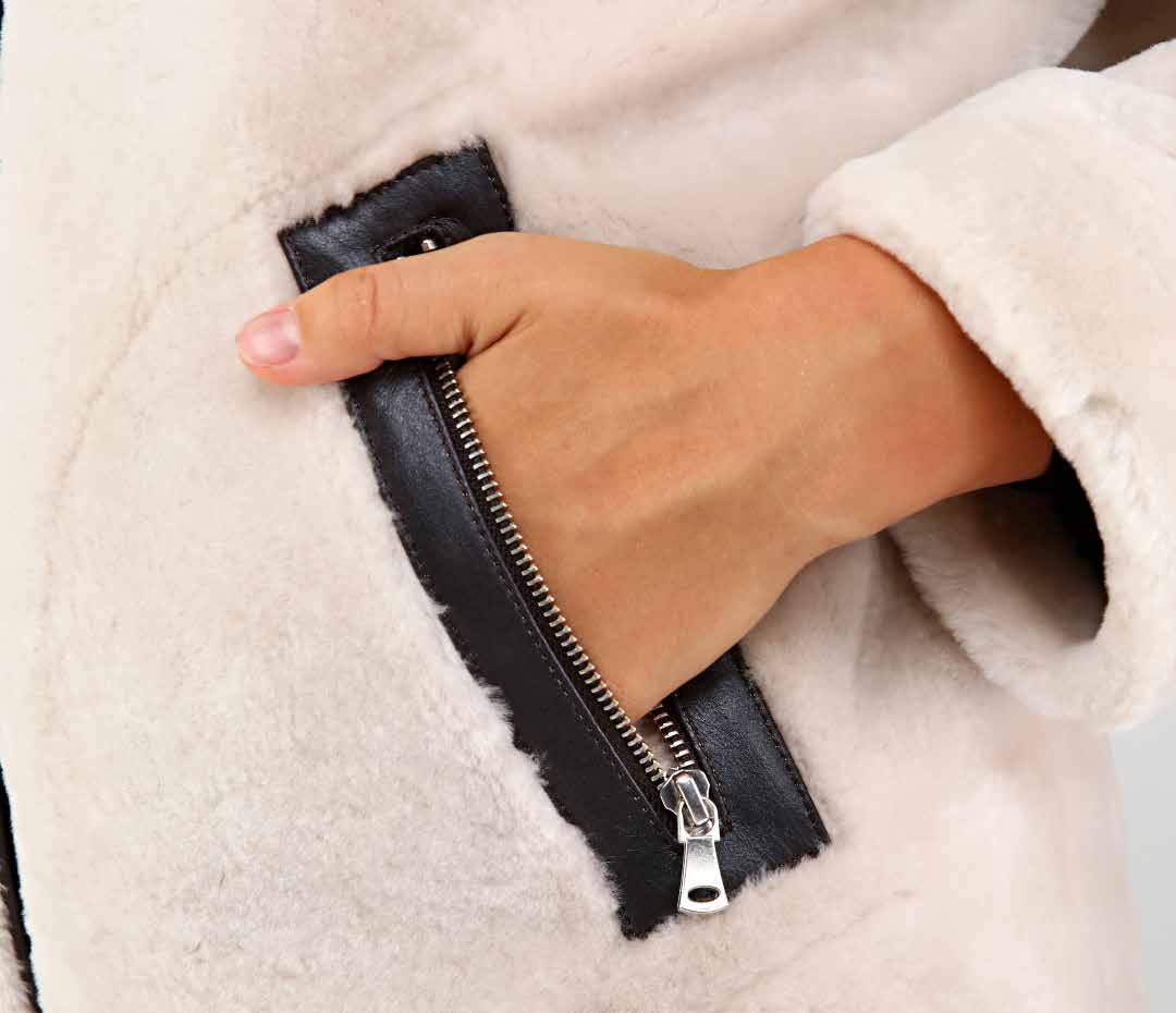 Hand opening a black zipper on a white fur coat