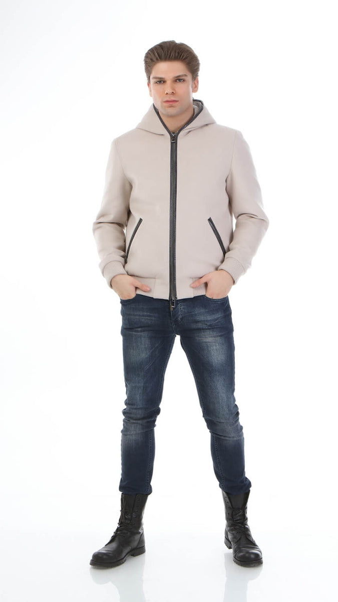 Man wearing a beige puffer jacket, blue jeans, and black boots on a white background