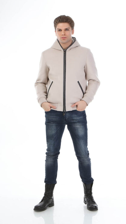 Man wearing a beige puffer jacket, blue jeans, and black boots on a white background