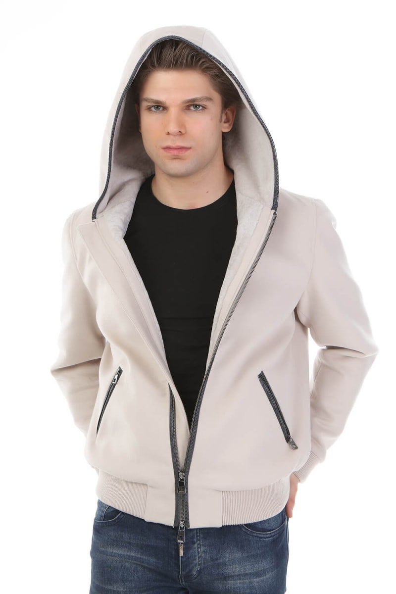 Man wearing a beige hoodie with a black shirt and blue jeans on a white background