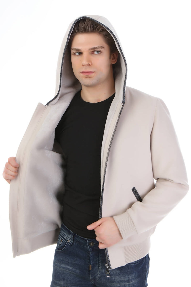 Man wearing a beige hooded jacket over a black shirt on a white background