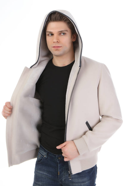 Man wearing a beige hooded jacket over a black shirt on a white background