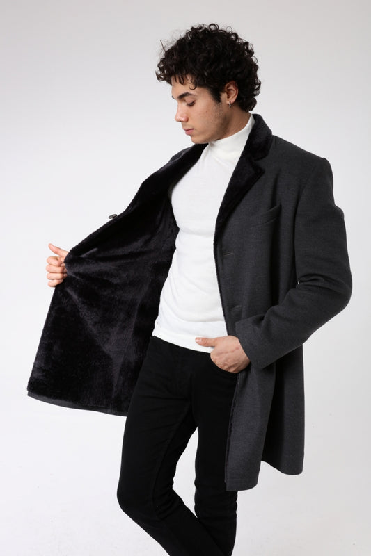 Man wearing a black coat over a white shirt and black pants on a white background