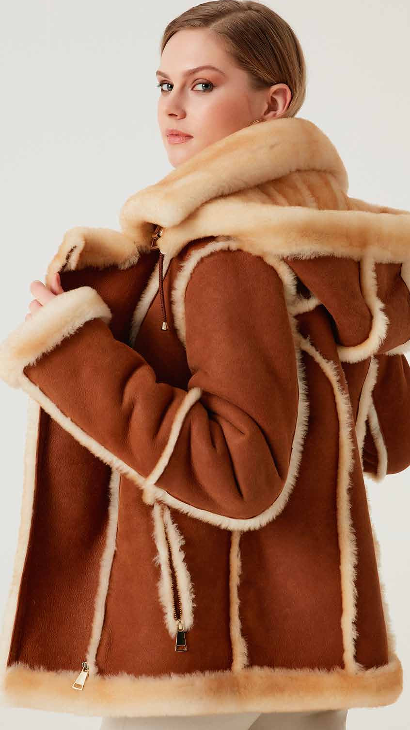 Brown coat with beige fur trim worn by a person on a white background