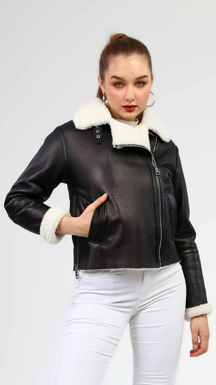Woman wearing a black leather jacket with white fur trim on a light gray background.