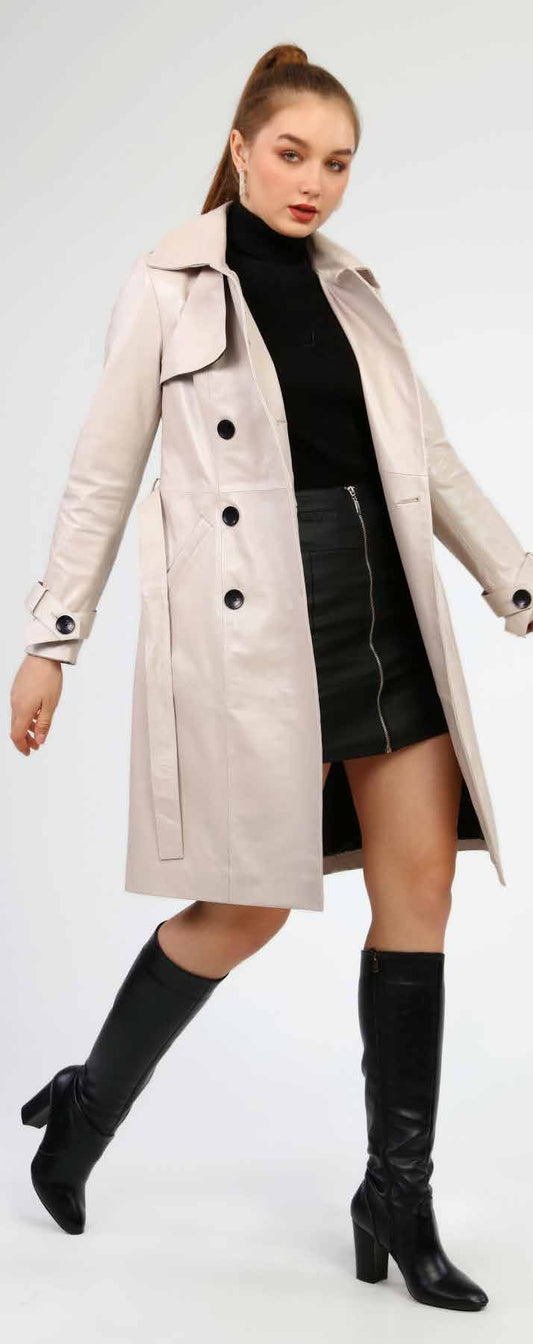 Woman wearing a beige trench coat, black turtleneck, and black skirt on a white background