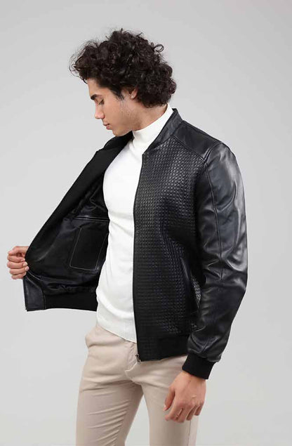 Man wearing a black leather jacket over a white shirt on a gray background