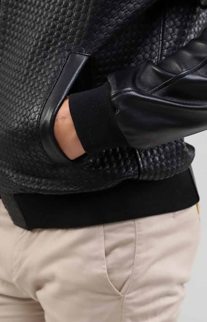 Man wearing a black leather jacket and gloves on a light gray background