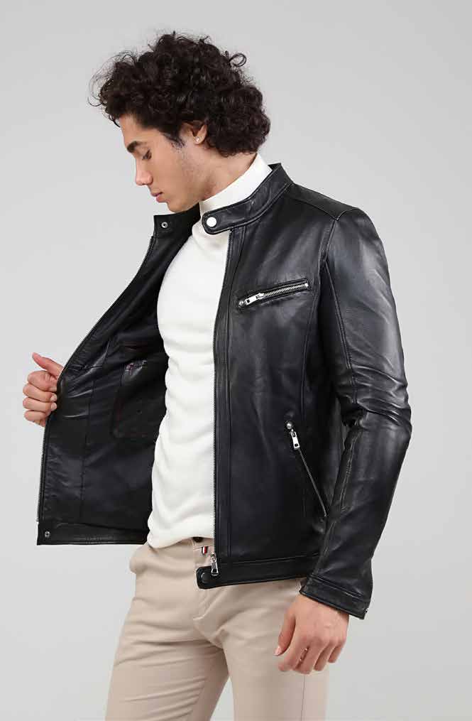 Man wearing a black leather jacket over a white shirt on a plain background
