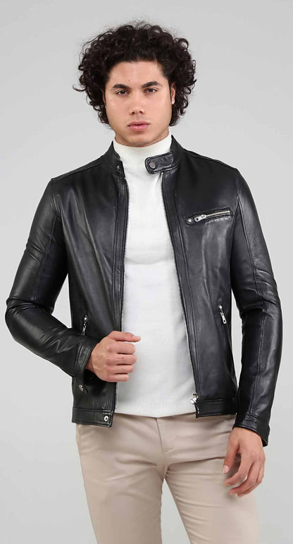 Man wearing a black leather jacket over a white turtleneck on a gray background