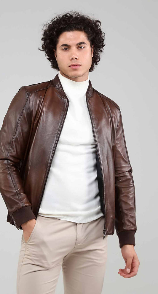 Man wearing a brown leather jacket over a white shirt on a gray background
