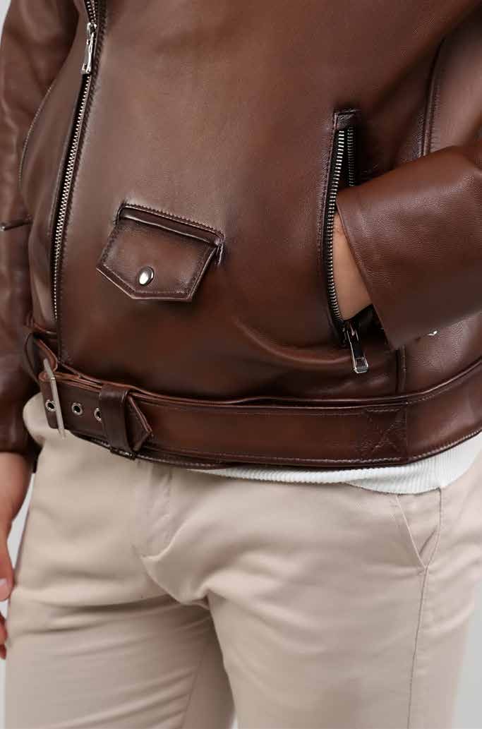 Brown leather jacket worn by a person with beige pants on a neutral background