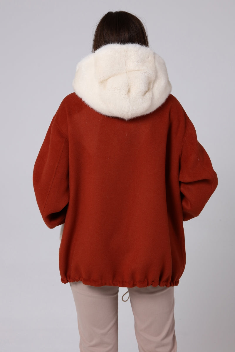 Woman wearing a red jacket with a white fur hood on a plain background