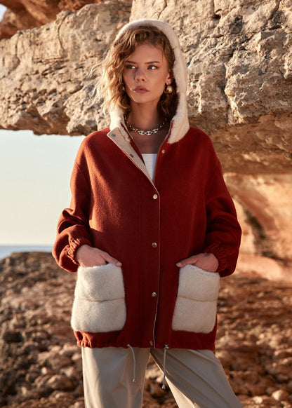 Woman wearing a red jacket with white fur lining in a natural setting
