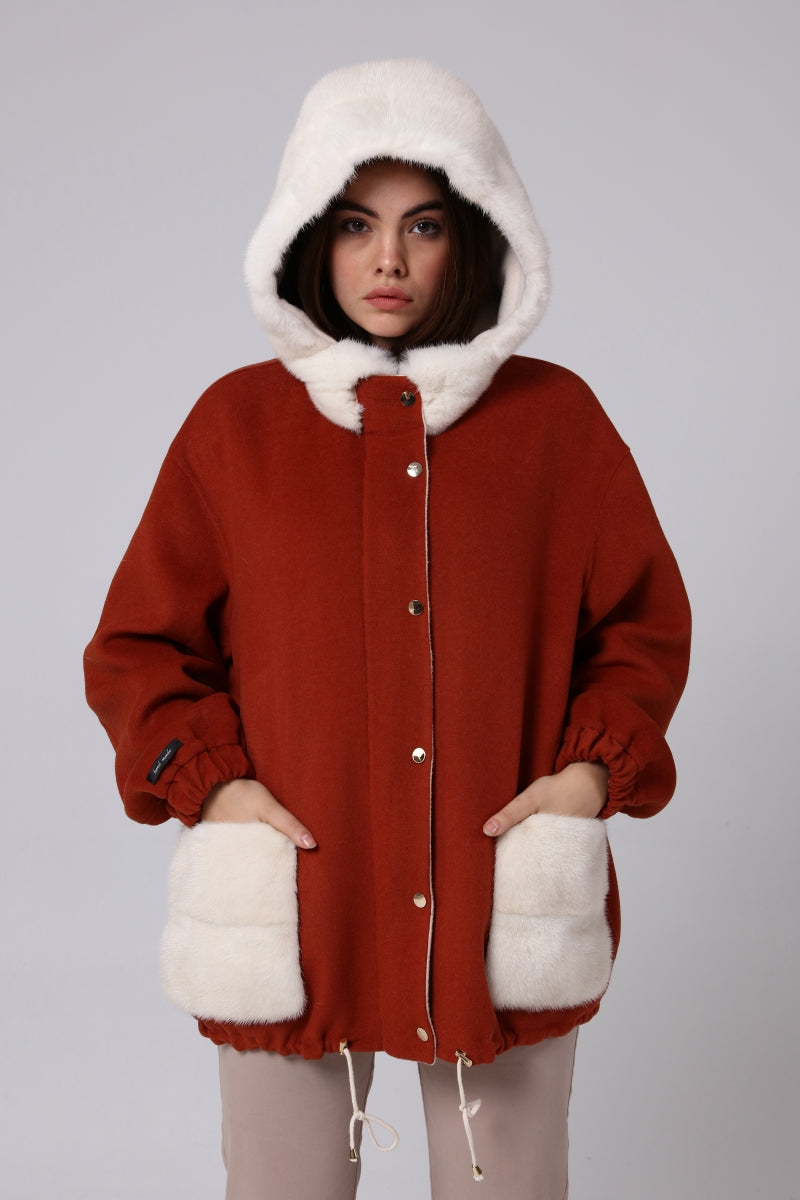 Woman wearing a red coat with white fur trim on a gray background