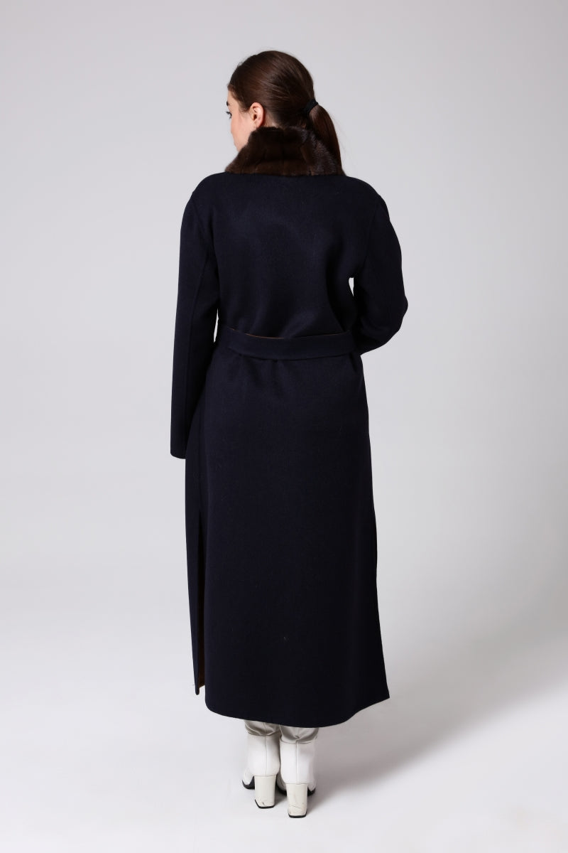 Woman wearing a long black coat on a white background