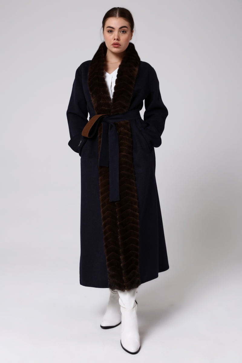 Woman wearing a long alpaca overcoat with mink fur on a white background